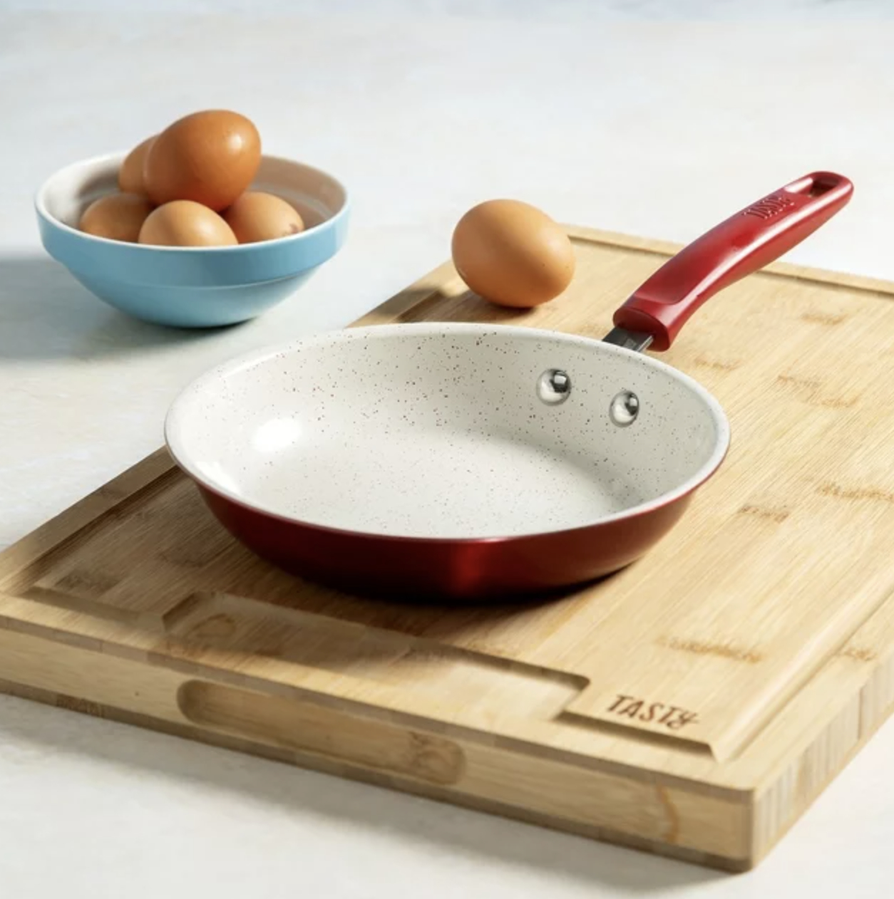 The red ceramic fry pan on cutting board