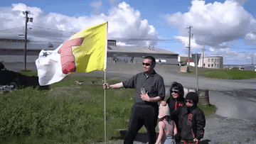 Nunavut flag waves next to a Nunavut family.