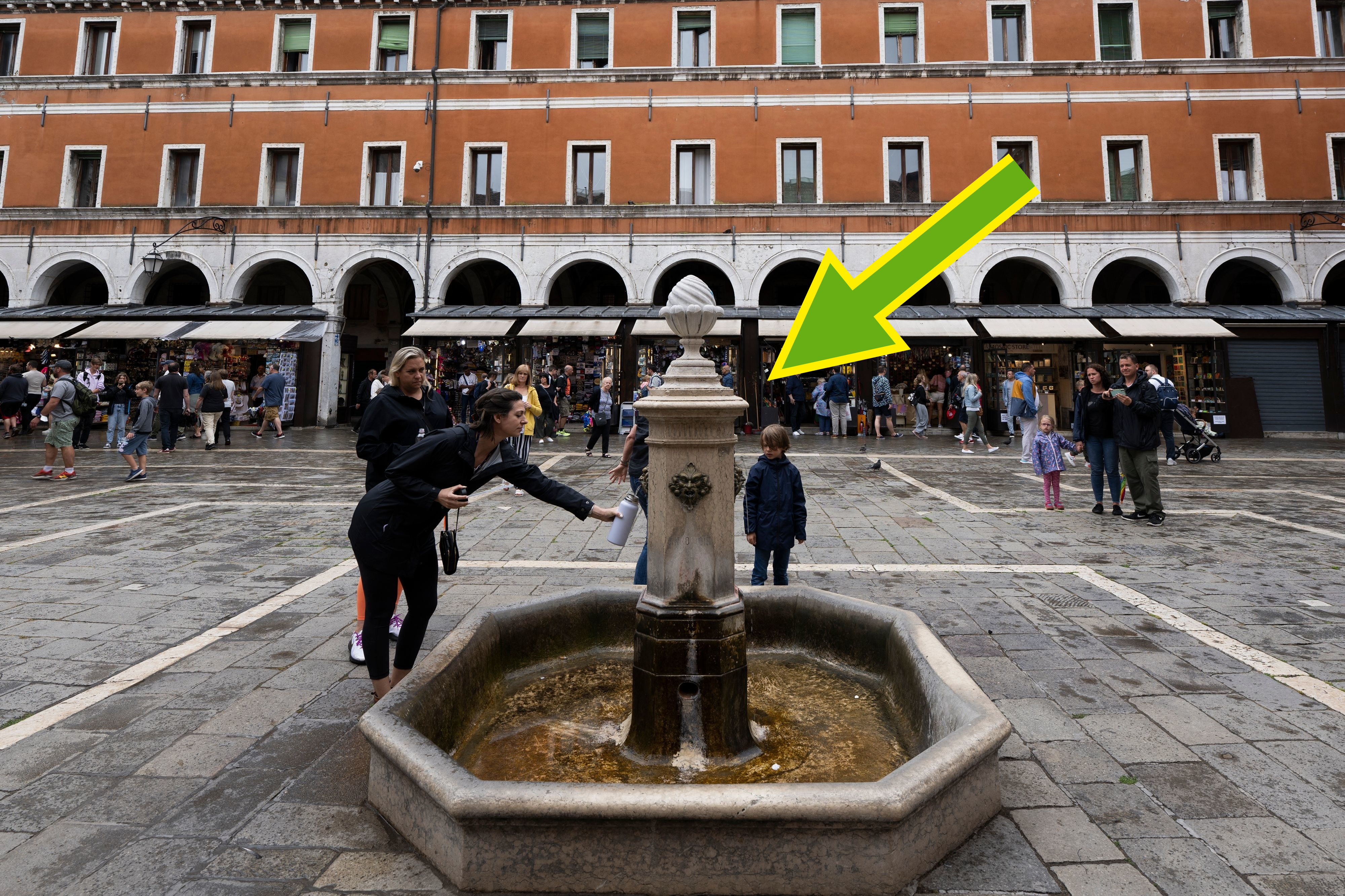 a person filling up a water bottle at a fountain in italy