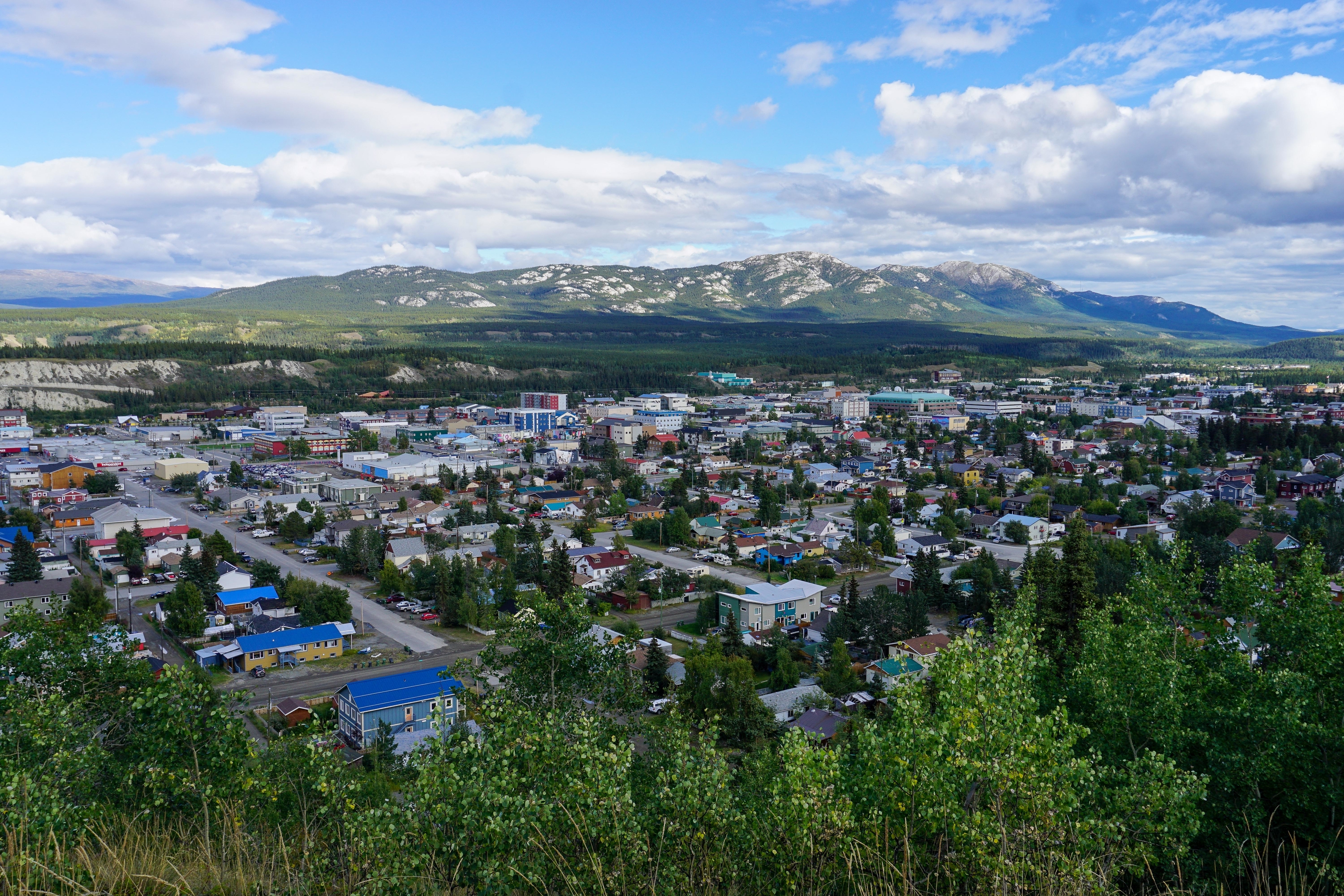 Drone shot of Yukon city with mountains in distance.