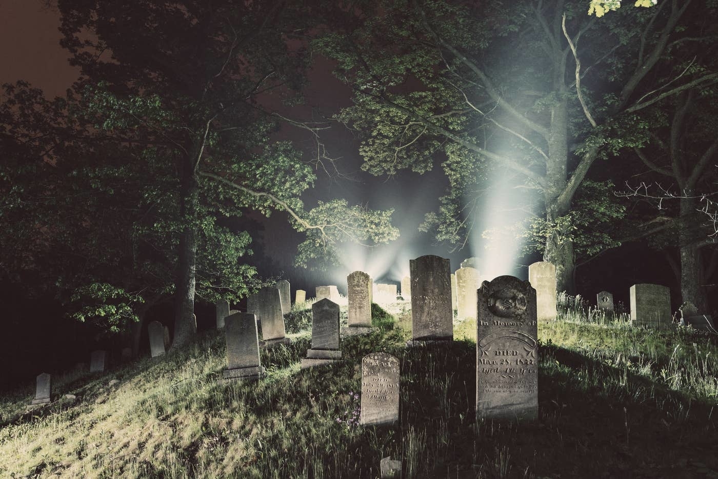 Grave stones are illuminated in a cemetery at night.
