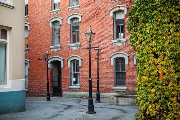 Red brick building with lamp posts in an alleyway.