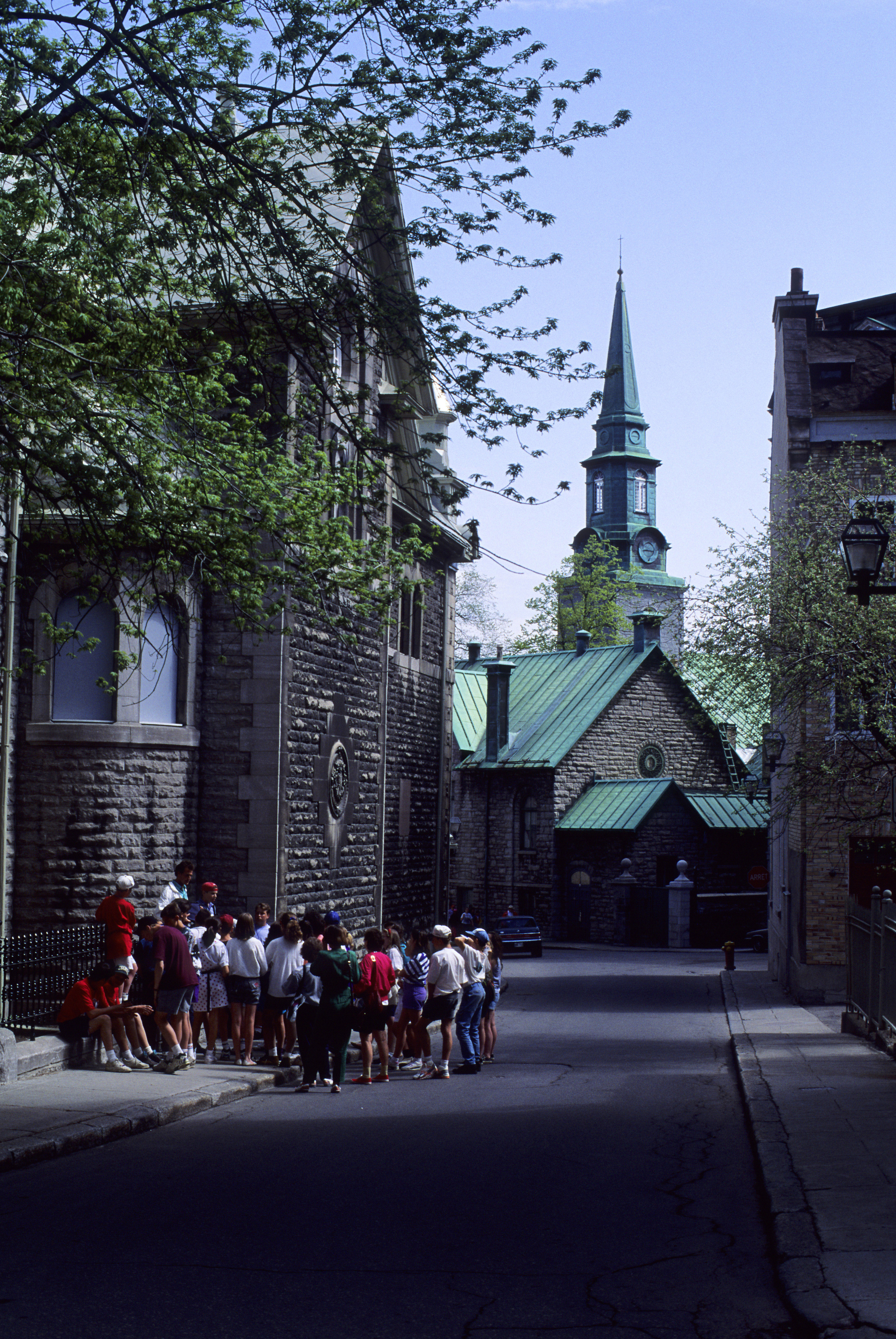 A cathedral can be seen down a street. A group of tourists huddles around it.