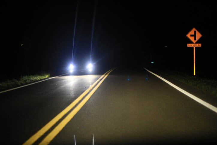 A dark road at night with a car&#x27;s headlights in the distance