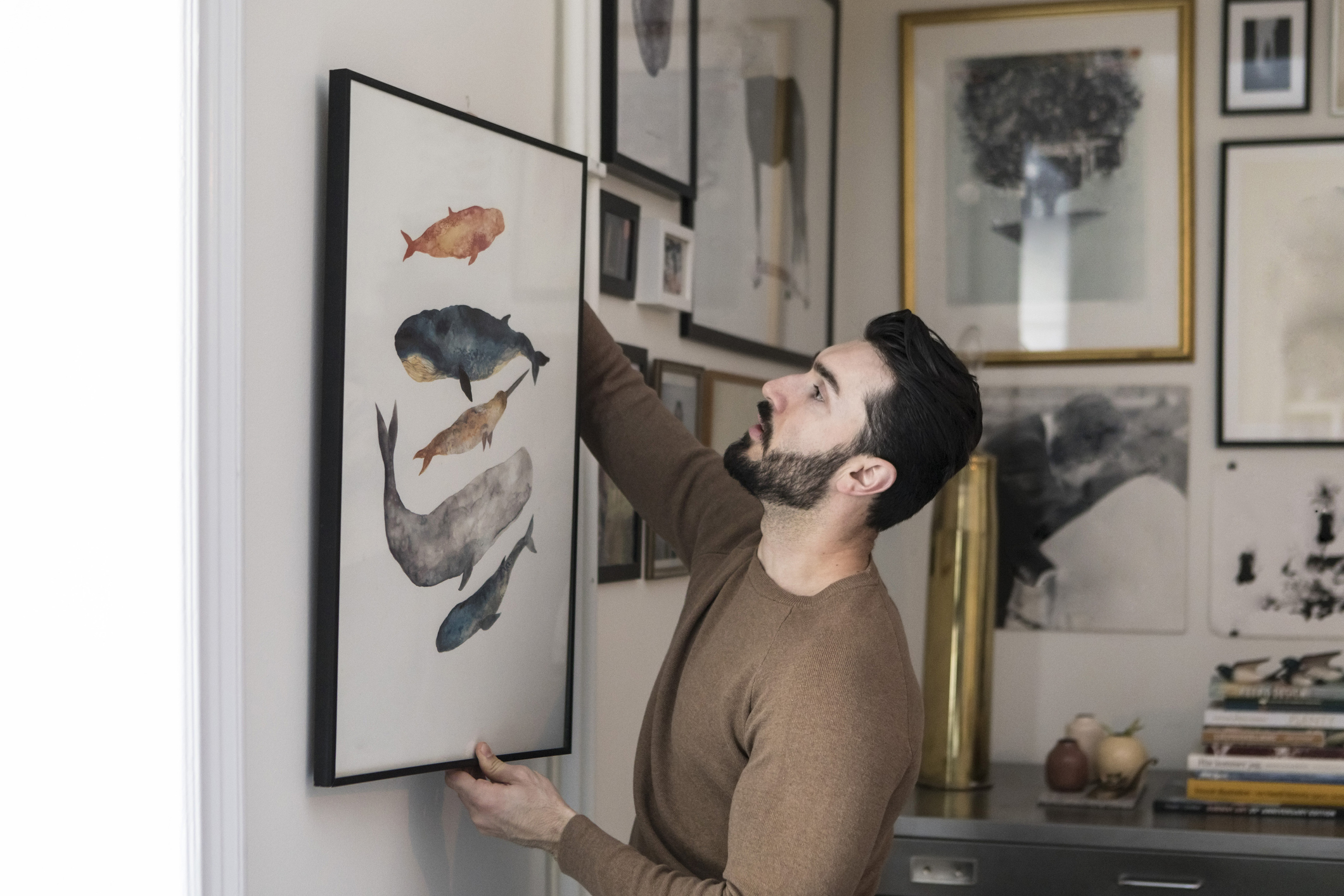 A man hanging up artwork
