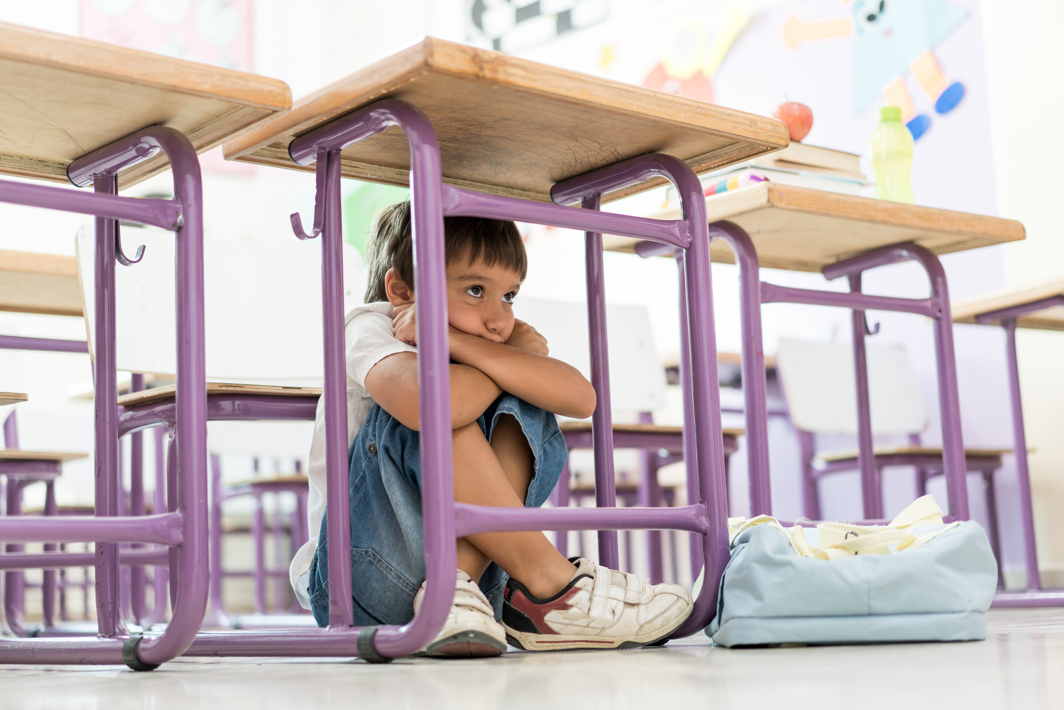 a child huddled under their desk