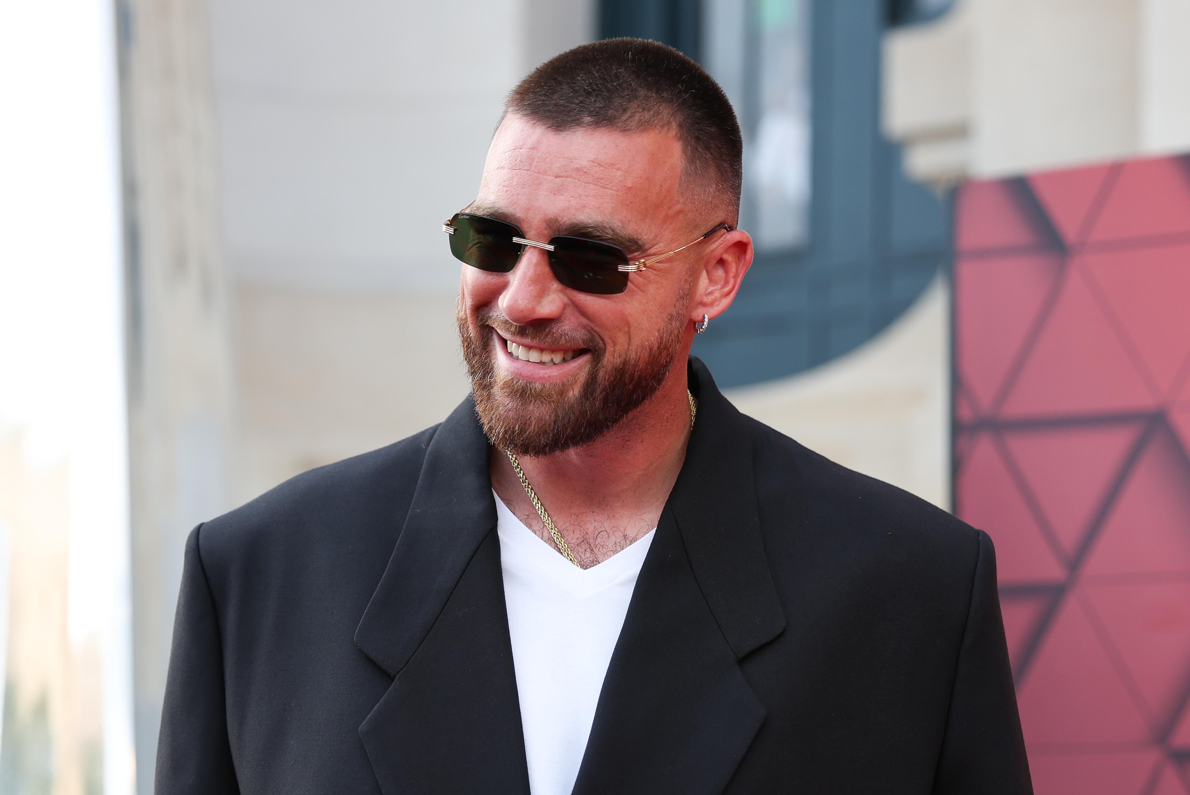 Close-up of Travis smiling and wearing sunglasses and a suit jacket