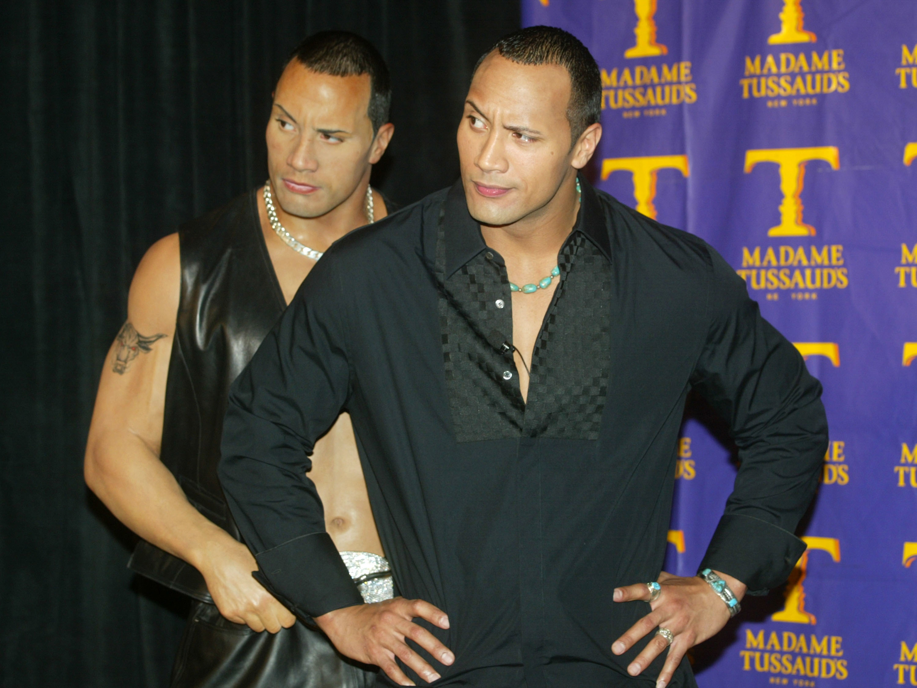 Close-up of Dwayne with his Tussauds wax figure, both with an eyebrow raised