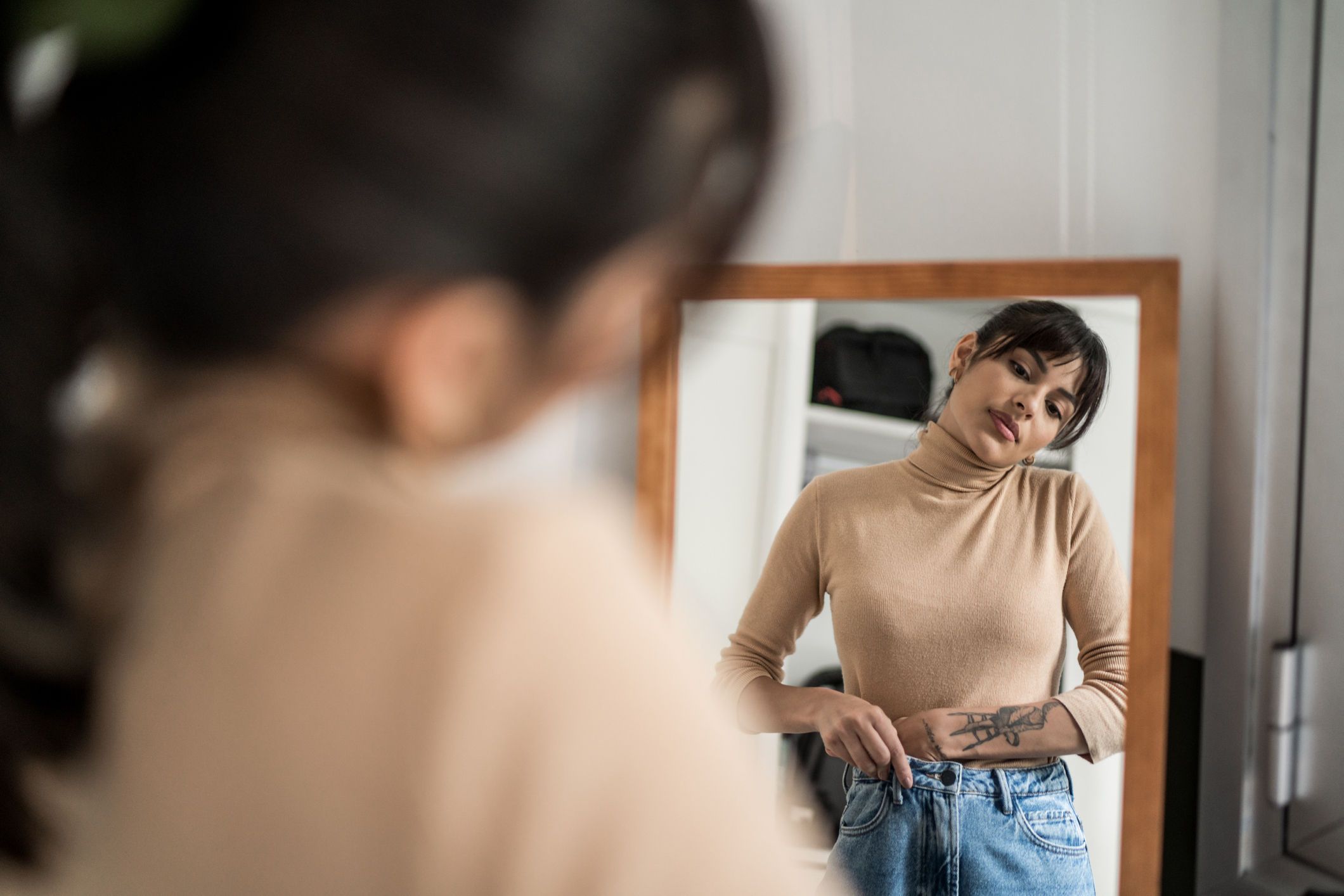 A woman trying on jeans in front of a mirror