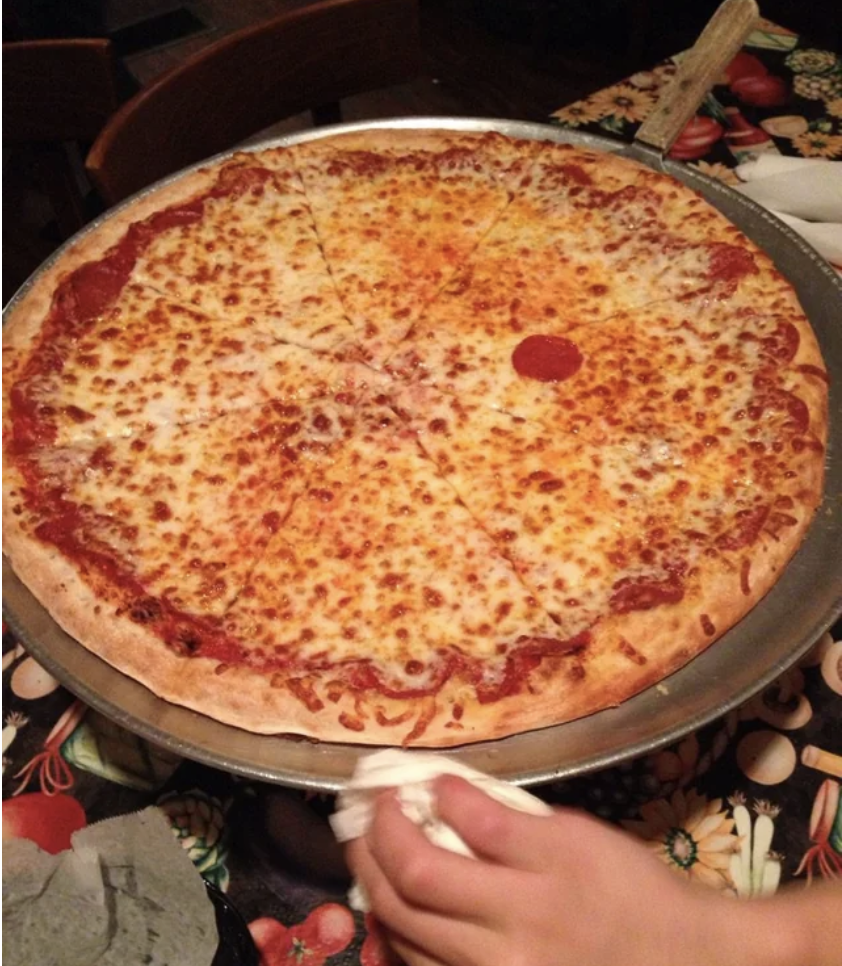 a cheese pizza with one pepperoni on it