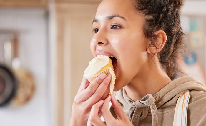 A woman biting a cupcake
