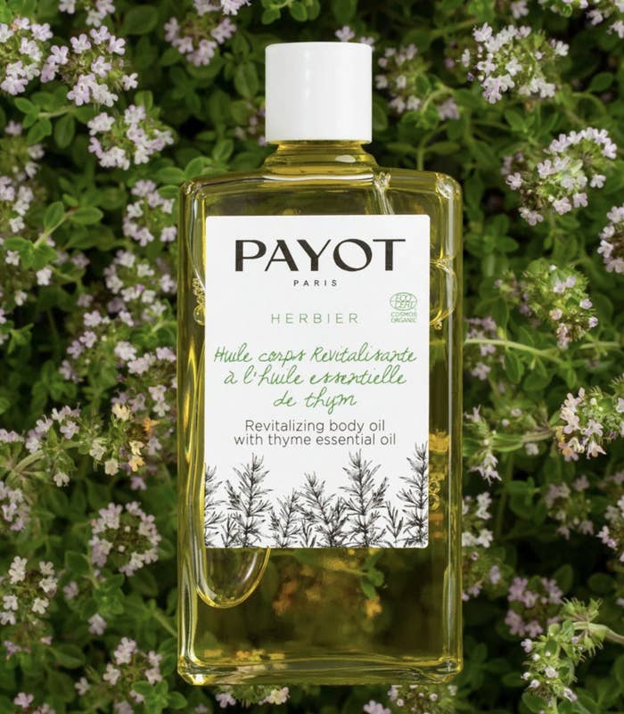 the body oil in its packaging in front of flowers