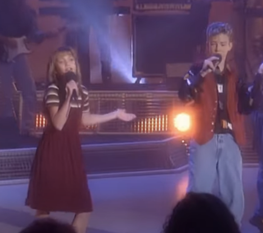 the two singing on stage as kids