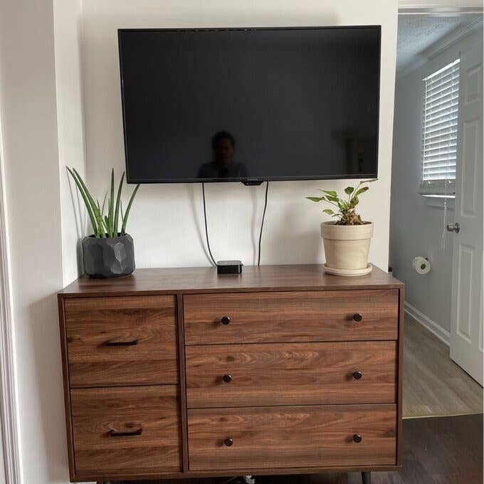 the drawer in brown below a tv, in a bedroom