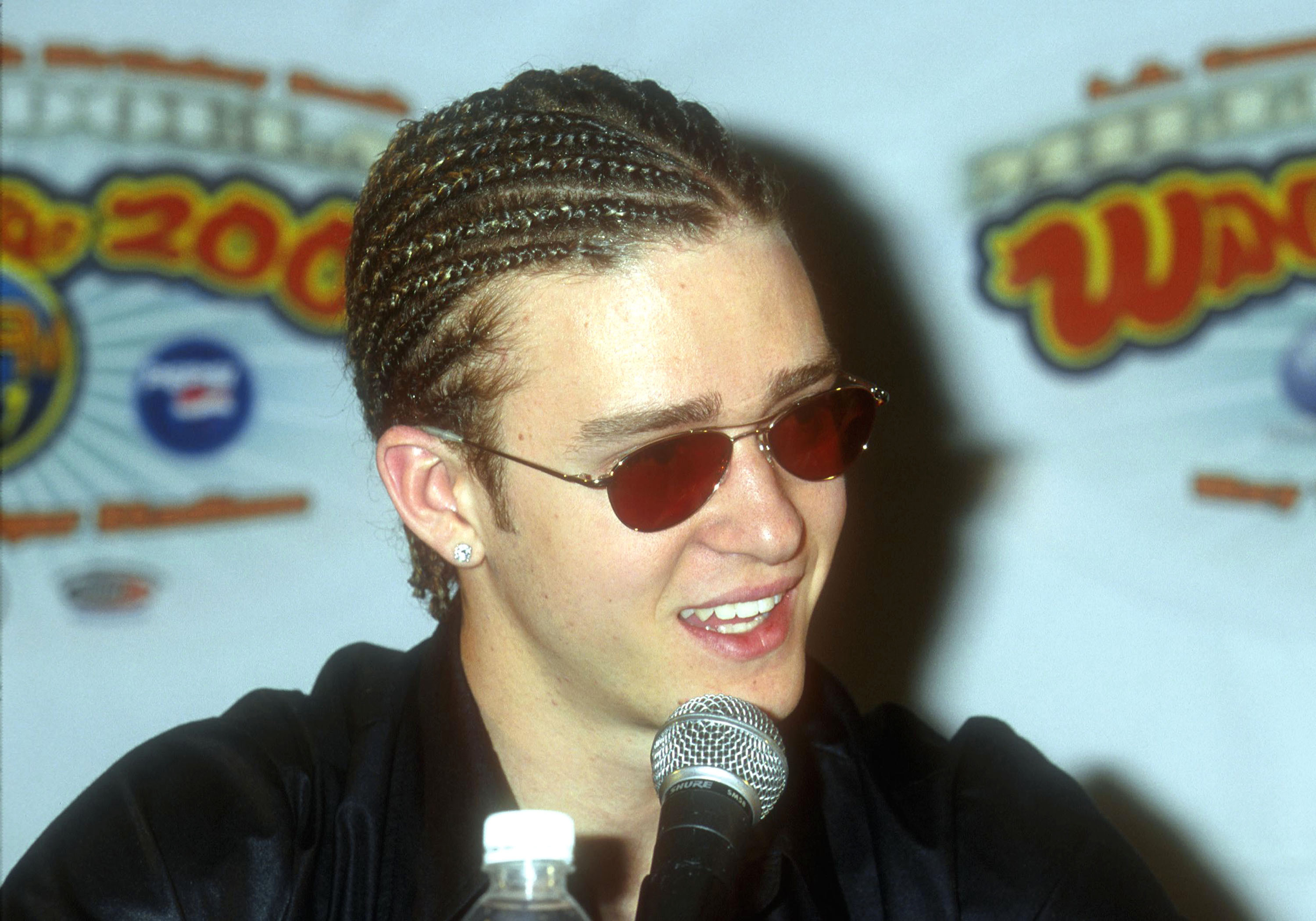 A closeup of Justin Timberlake with his hair in cornrows while speaking at an event