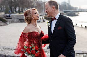 A bride in a red dress smiling at her husband.