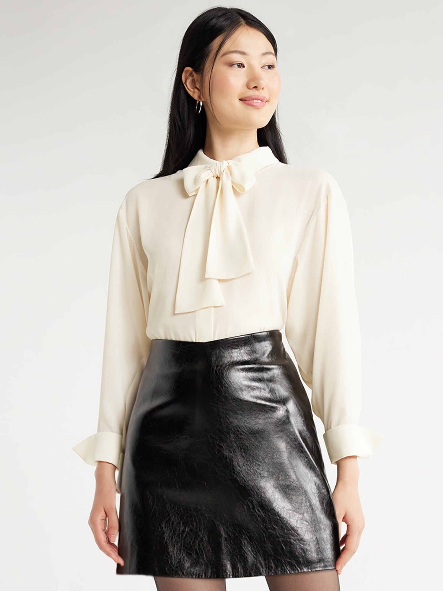 a model wearing the cream-colored top with a black leather skirt