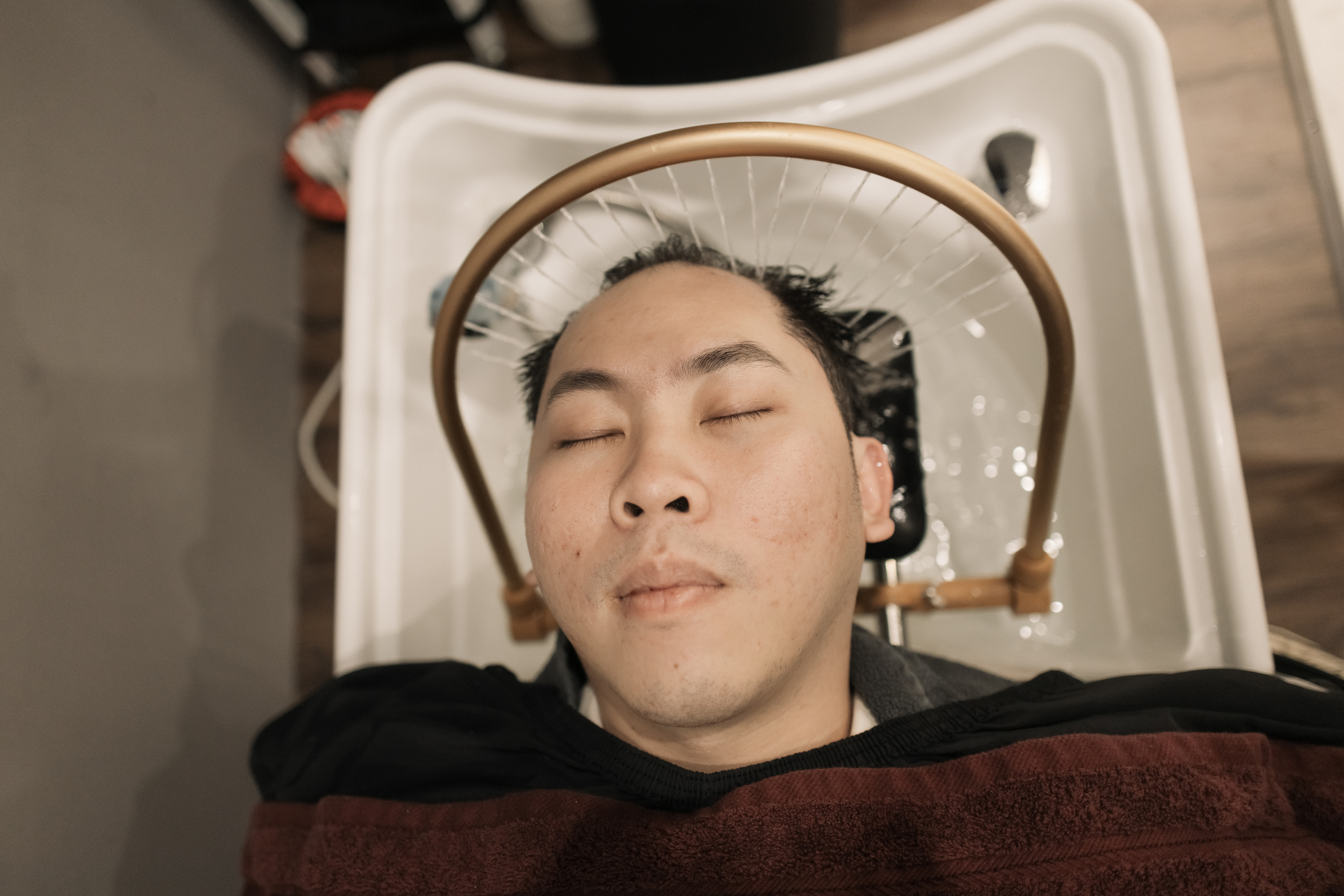 A man is receiving a scalp massage treatment