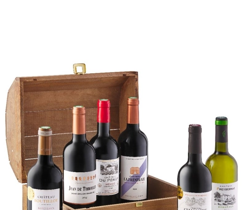 Several bottles of Bordeaux in and around a wooden chest