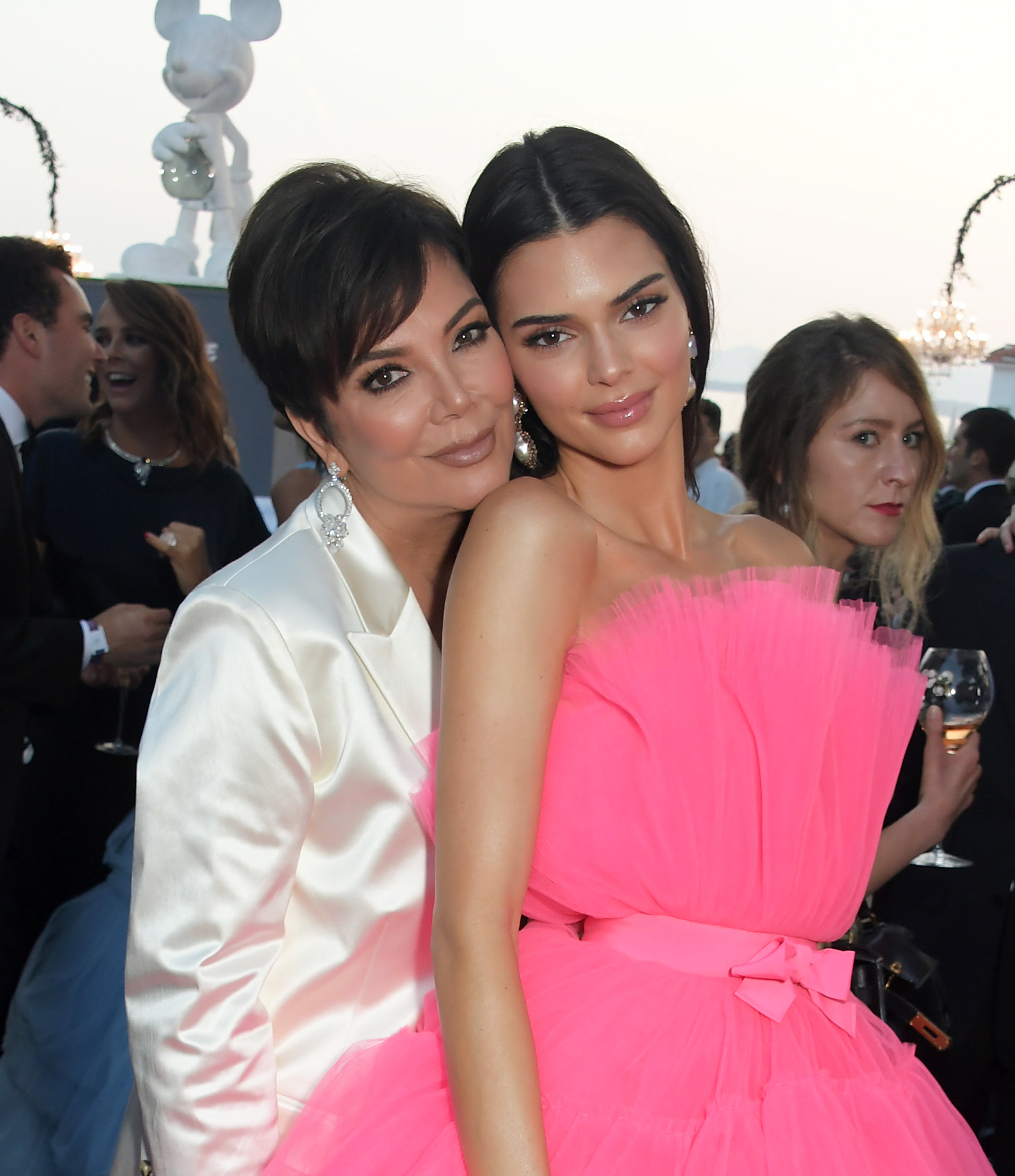 Closeup of Kris cuddling up behind Kendall Jenner on a red carpet as they pose for a picture