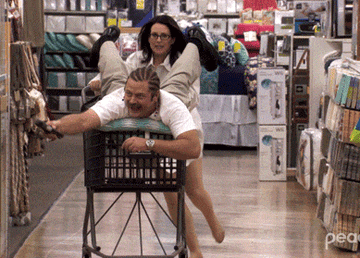 gif of someone pushing someone else in a cart while shopping