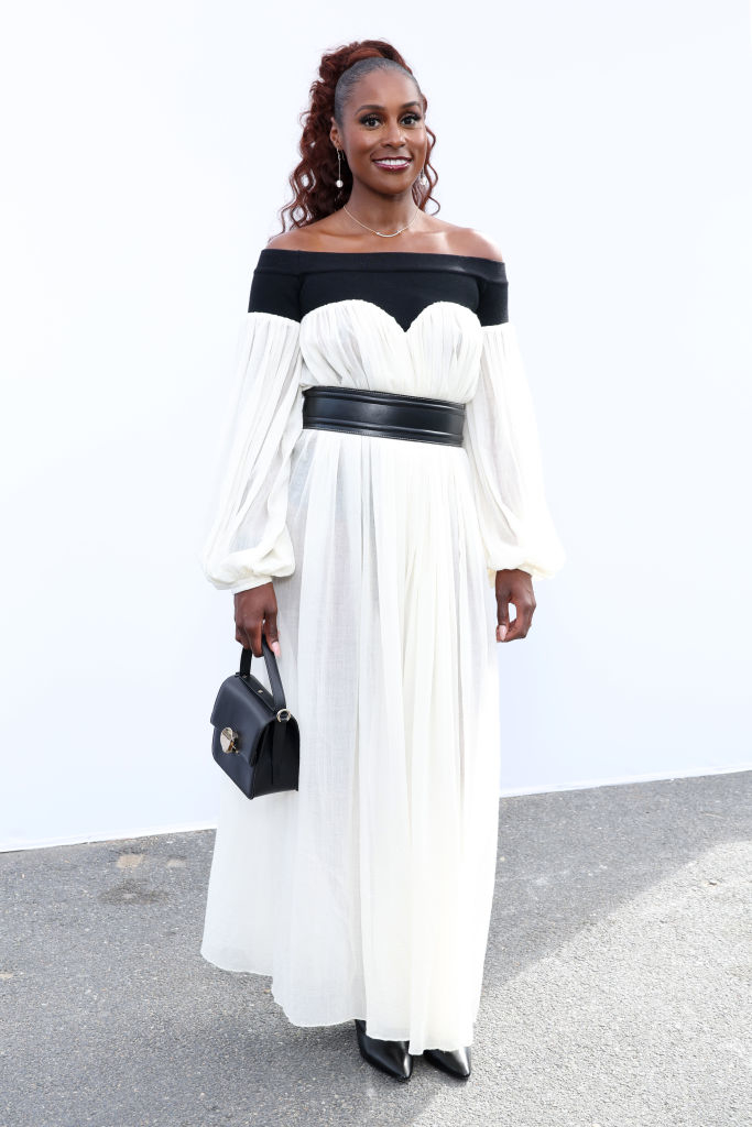 she's standing outside wearing a long dress and holding a small purse