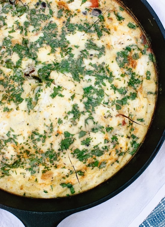 a frittata ini a cast iron skillet cut into slices and topped with cilantro