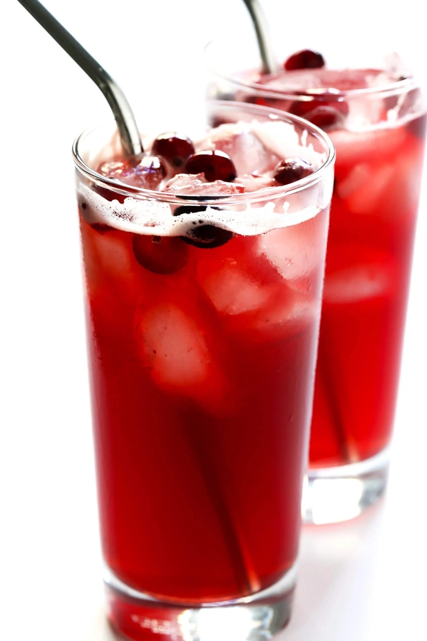 a cranberry bourbon fizz in a glass with a metal straw and topped with more cranberries