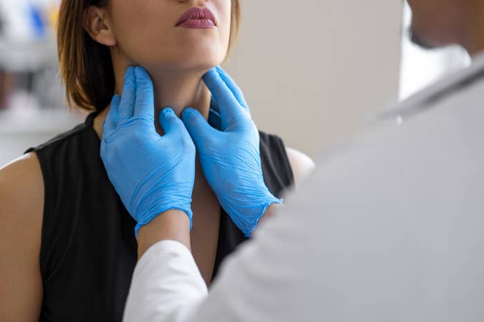 Doctor feeling a woman&#x27;s throat during a checkup