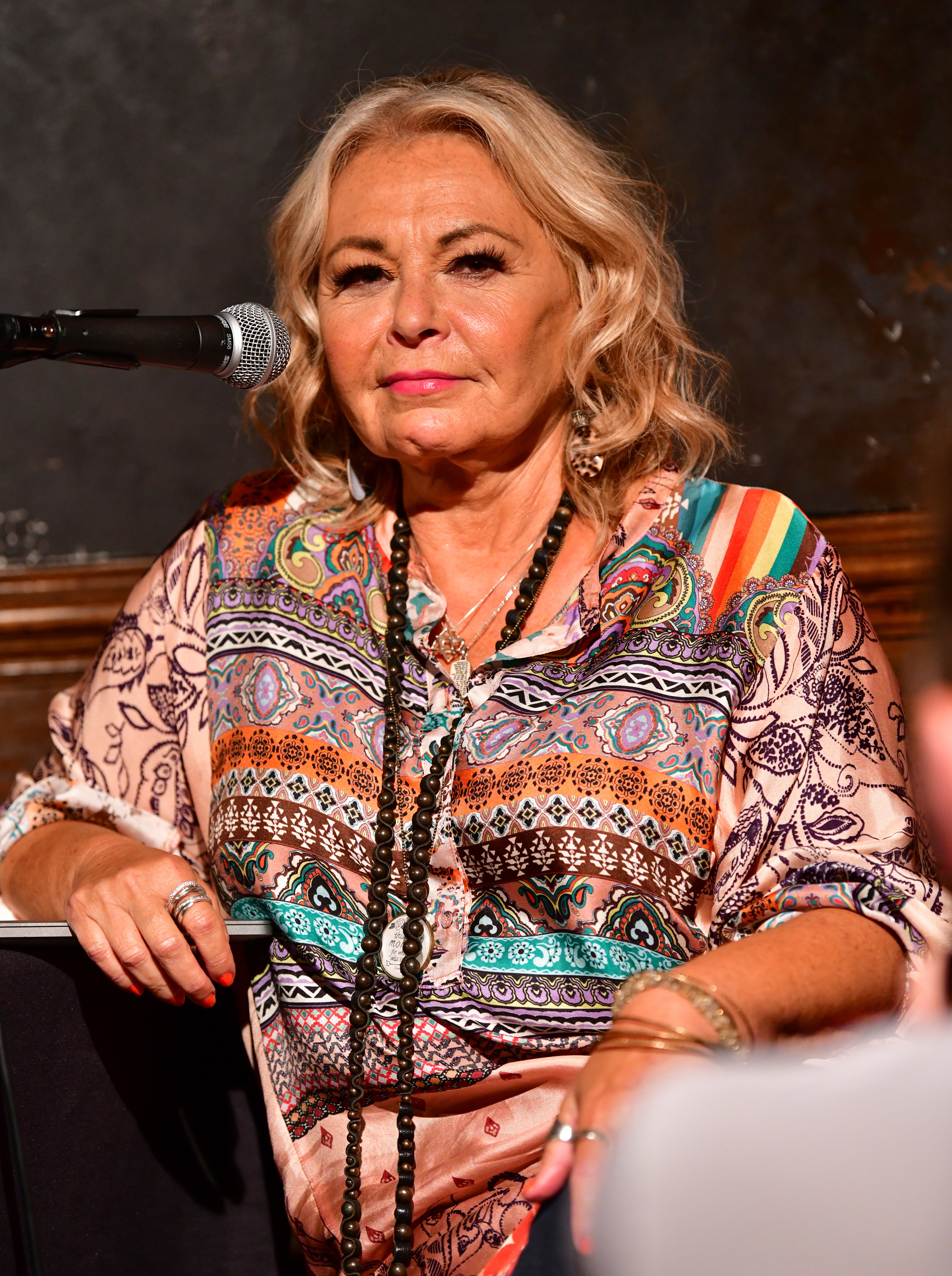 Close-up of Roseanne sitting at a microphone