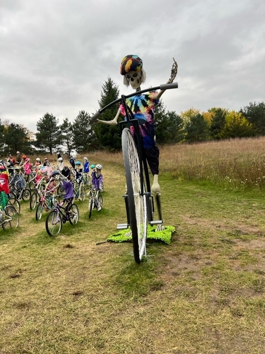 A skeleton riding a unicycle on the grass