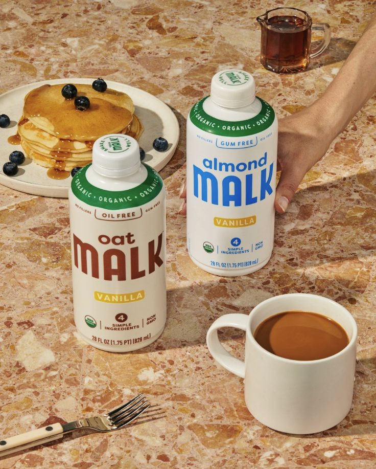 two malk bottles with a coffee and pancakes next to it