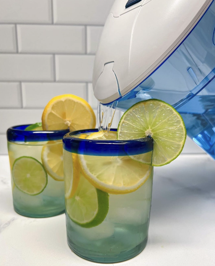 zerowater pitcher pouring water into glasses with lemon and limes slices