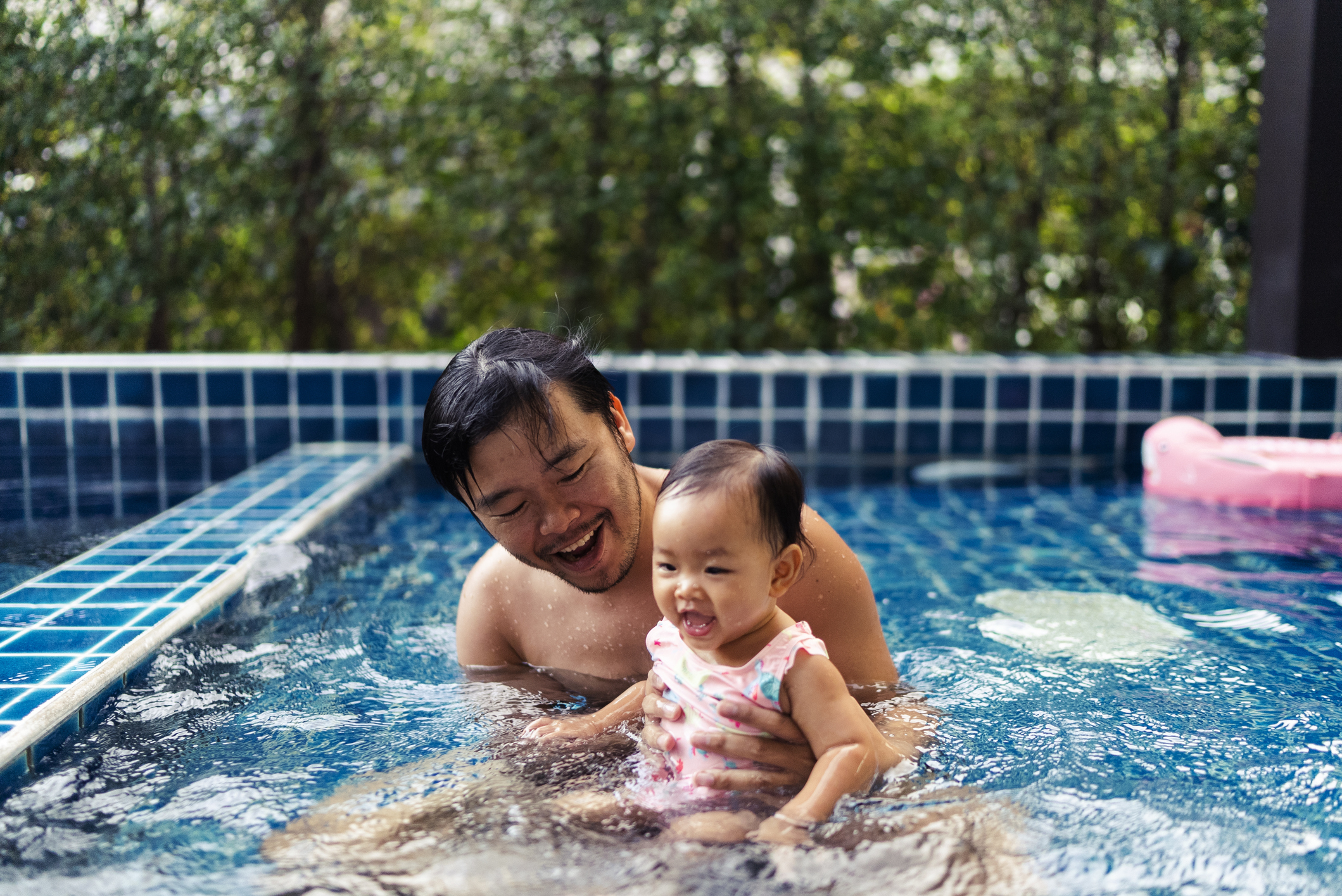 A father and daughter are swimming in a pool