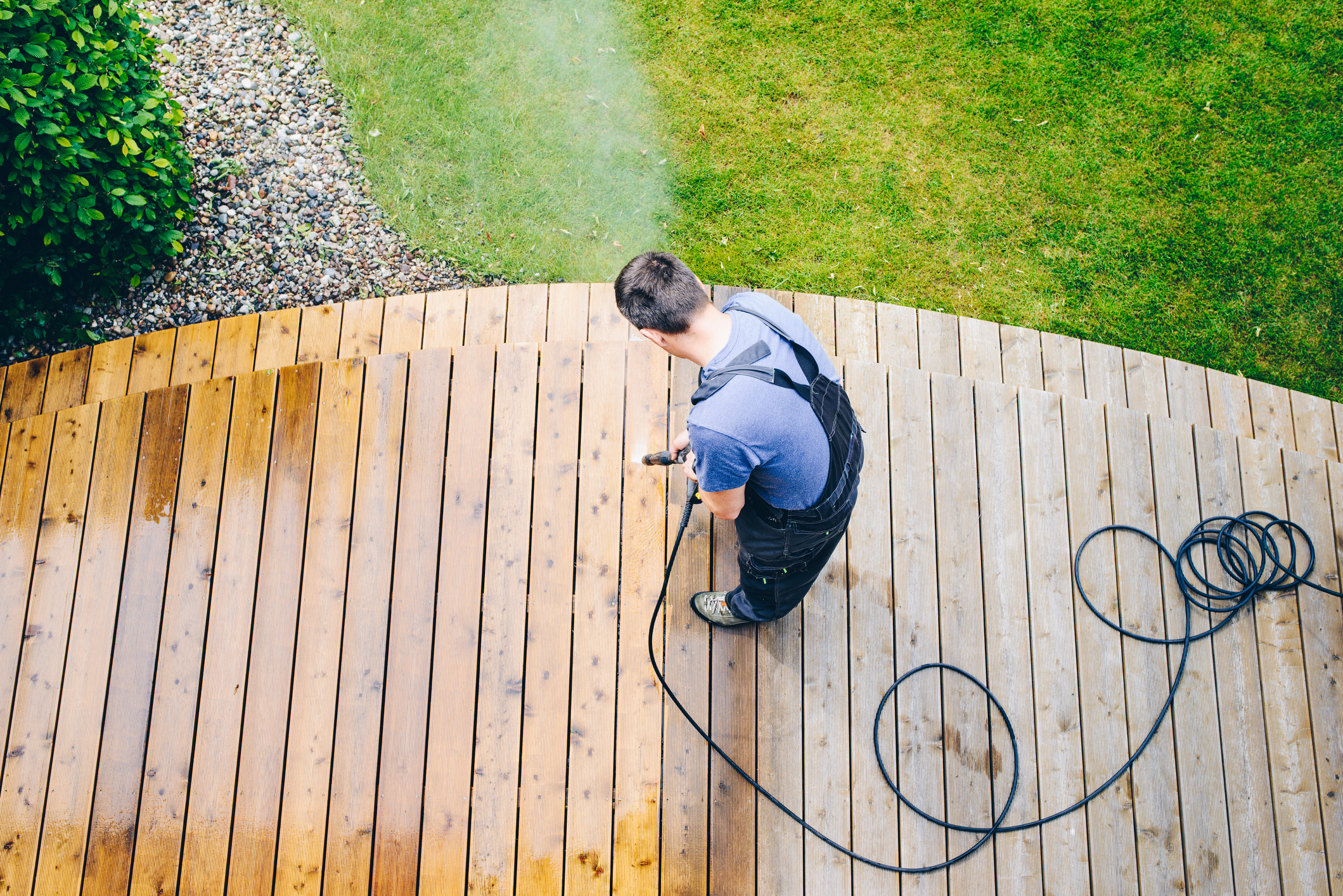 A man is power-washing his deck