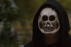 Person in skeleton mask and a hoodie. The hood is up, so you can't see anything about the person except for part of their neck.