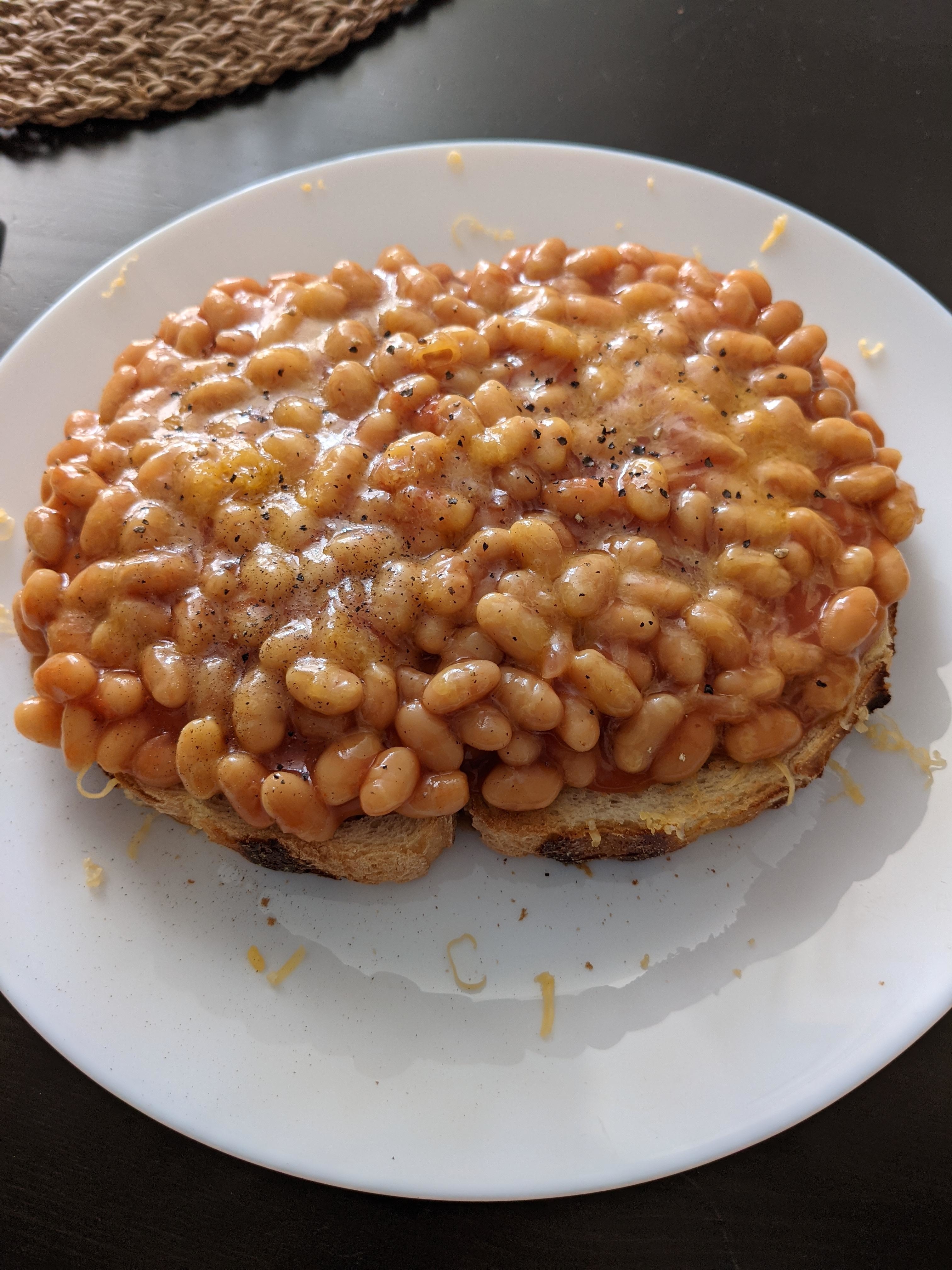 Close-up of baked beans and shredded cheese on top a piece of toast