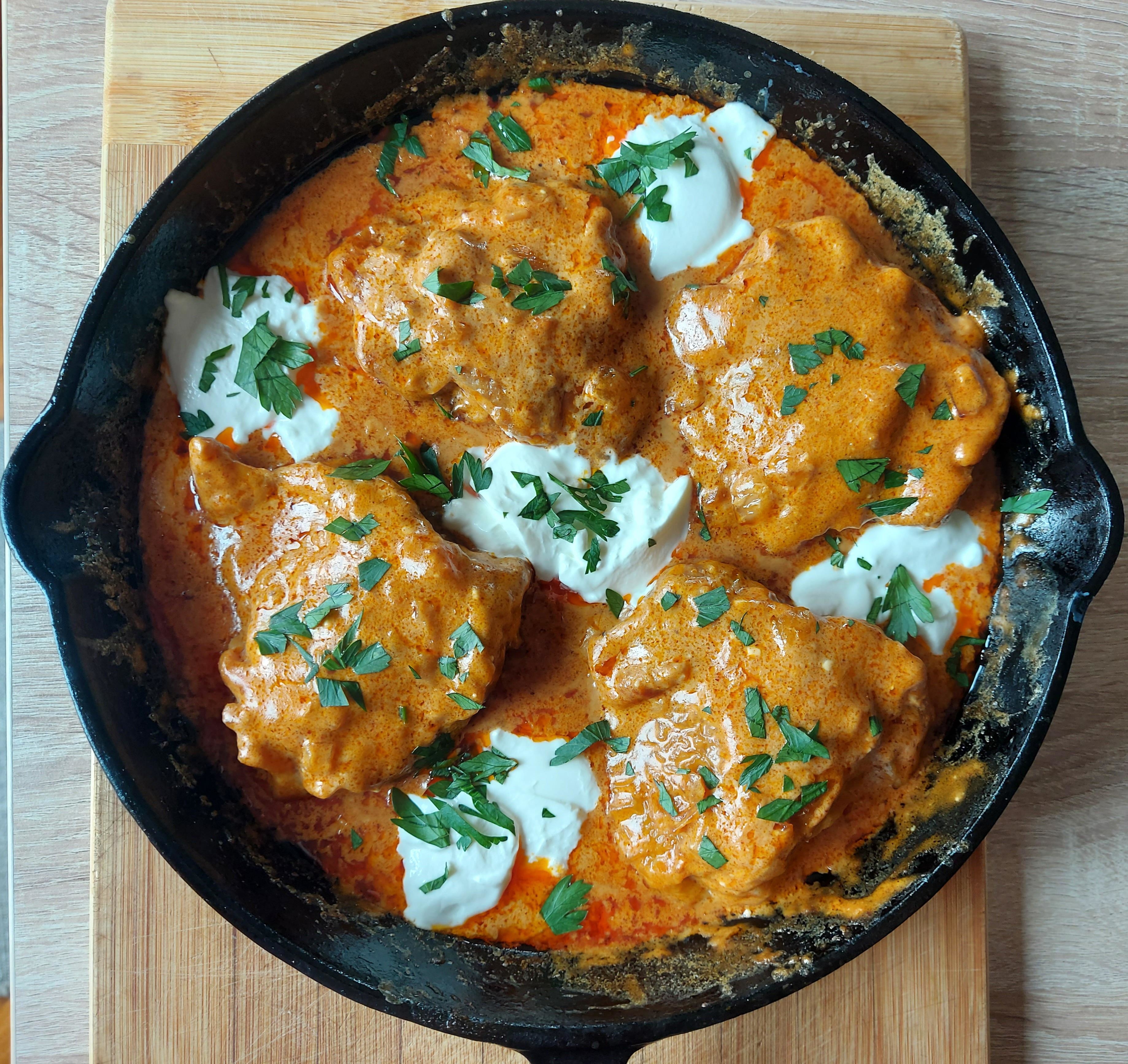 Chicken paprikash in a cast-iron pan with herbs and sour cream on top