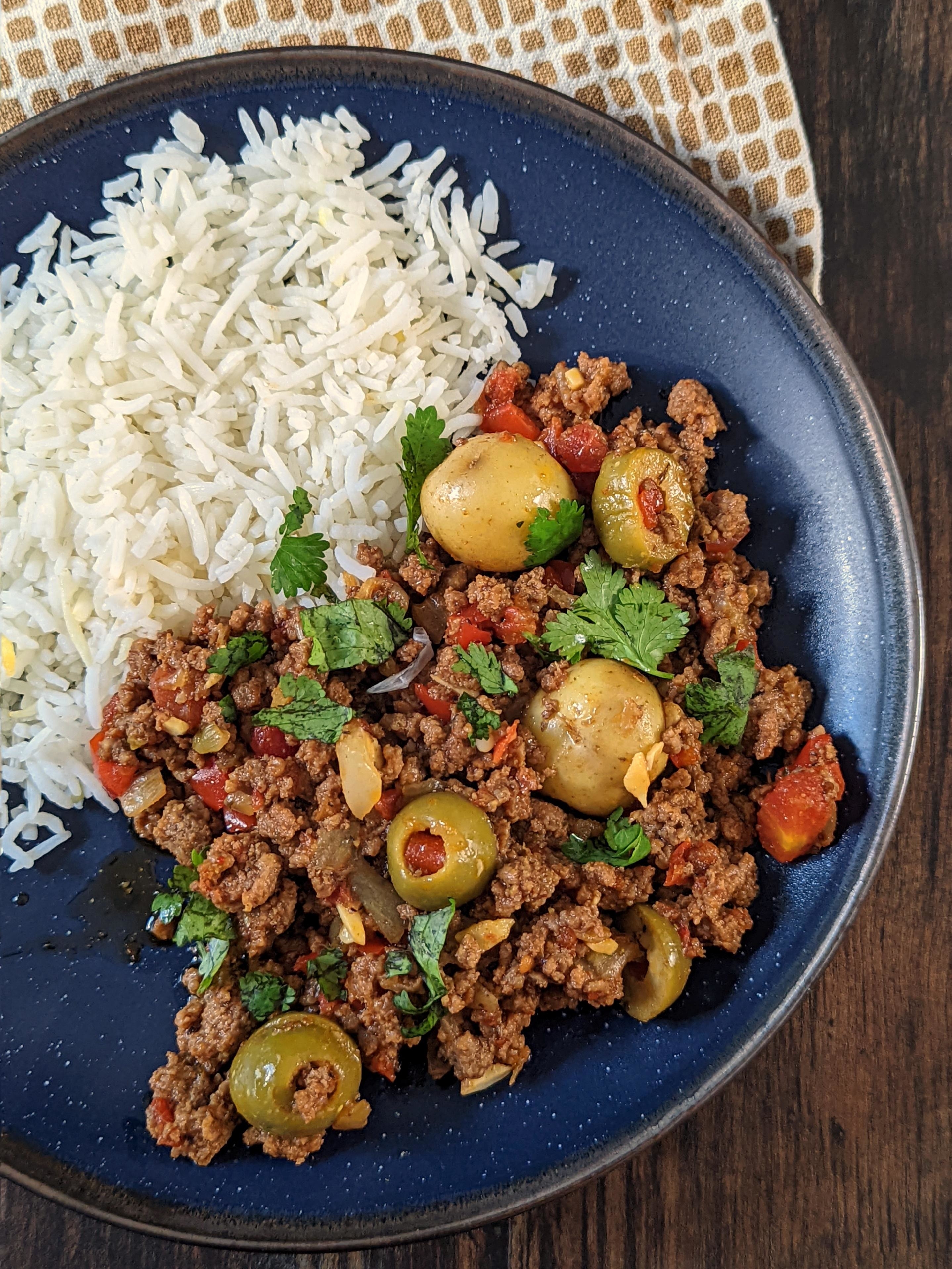 Cuban beef picadillo with olives, potatoes, and herbs served with a side of rice