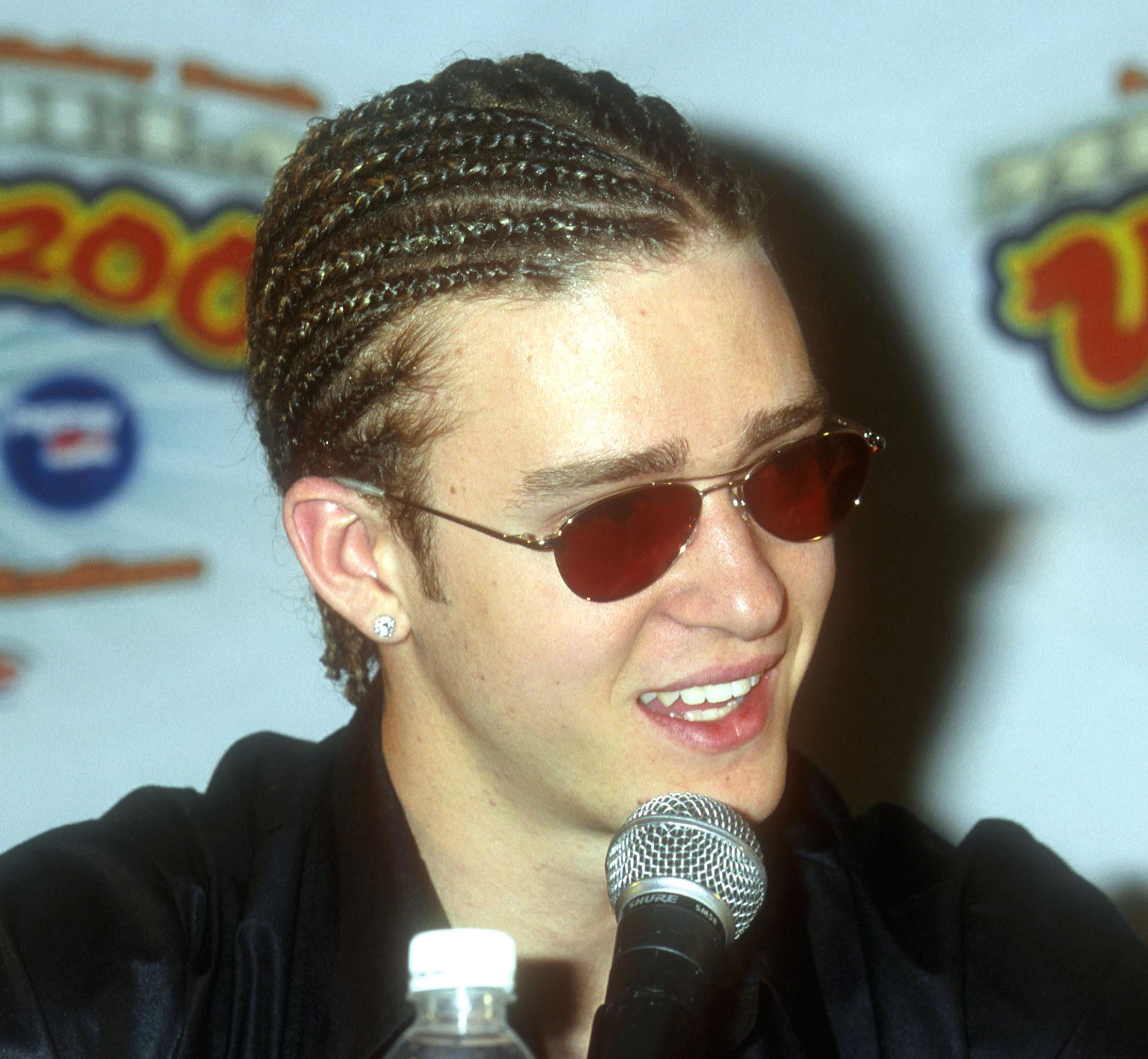 Close-up of Justin in front of a microphone and wearing cornrows