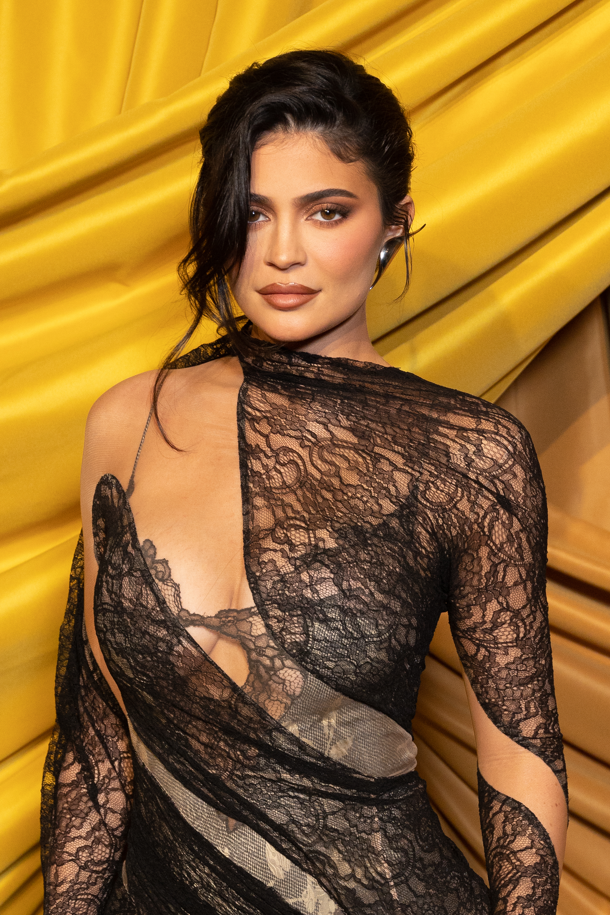 Close-up of Kylie at a media event in a swirling, lacy outfit