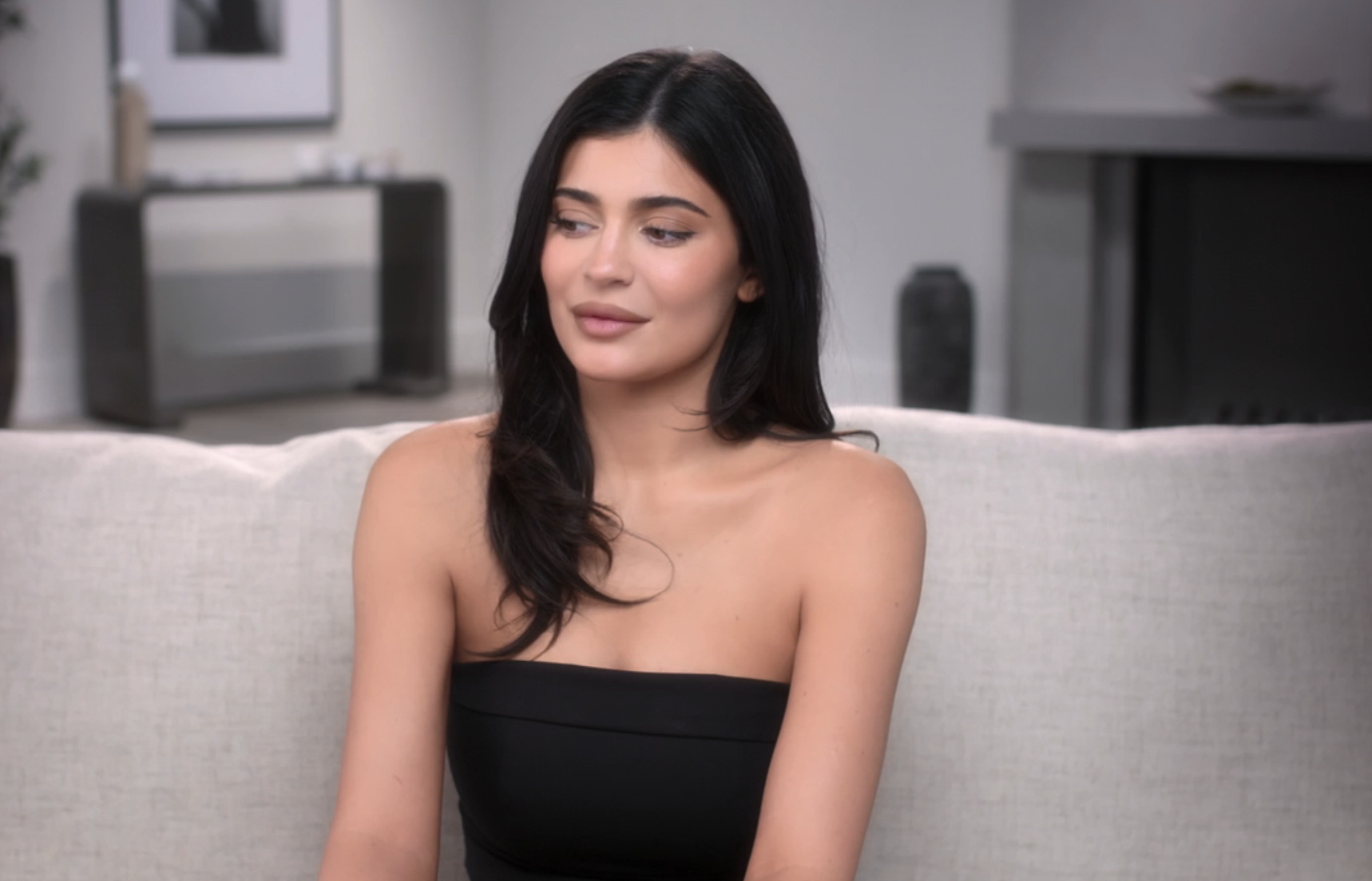 Close-up of Kylie sitting and wearing a strapless top