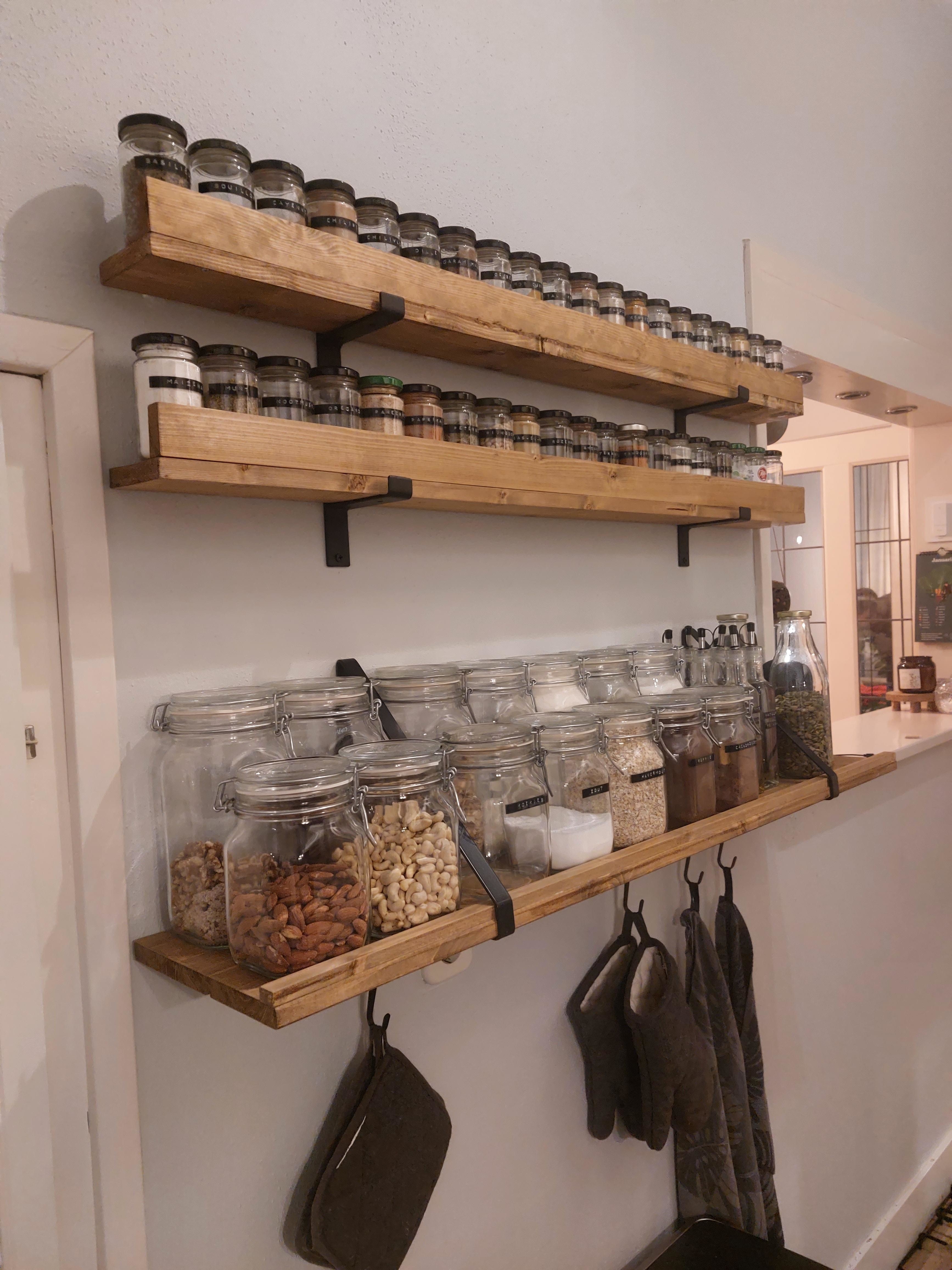Wood shelves on kitchen wall storing dry goods, spices, and canisters of food