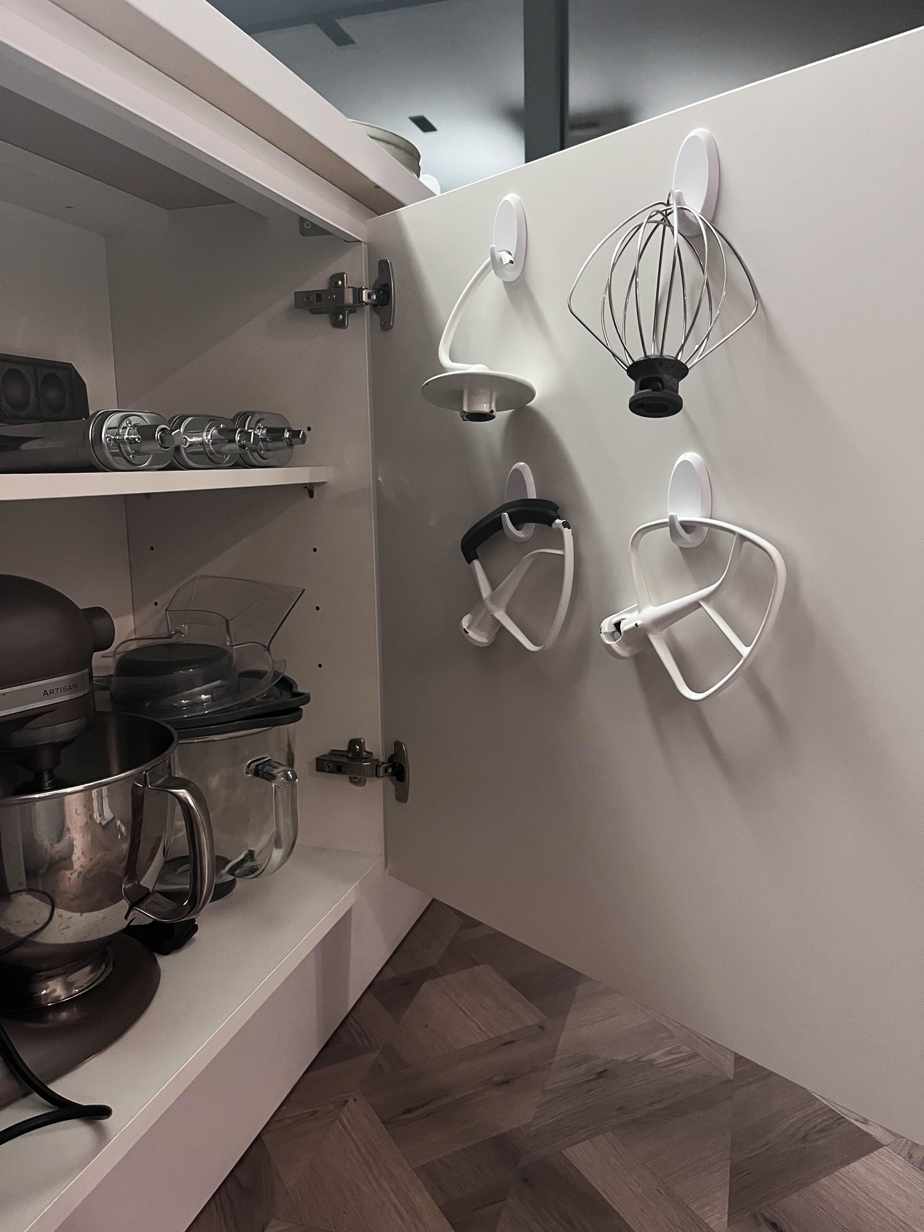 Various mixer attachments hanging via Command hooks on a cabinet door
