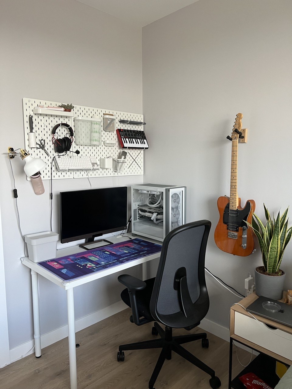 Pegboards above a desk holding music supplies and other objects