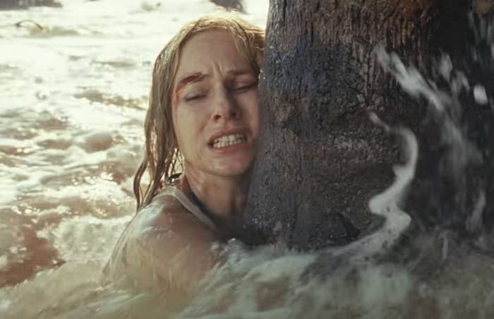 injured woman clutching a tree in a sea of water