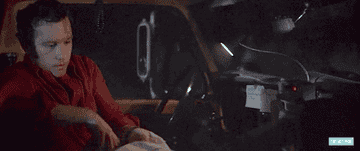 person unfolding a map in their car