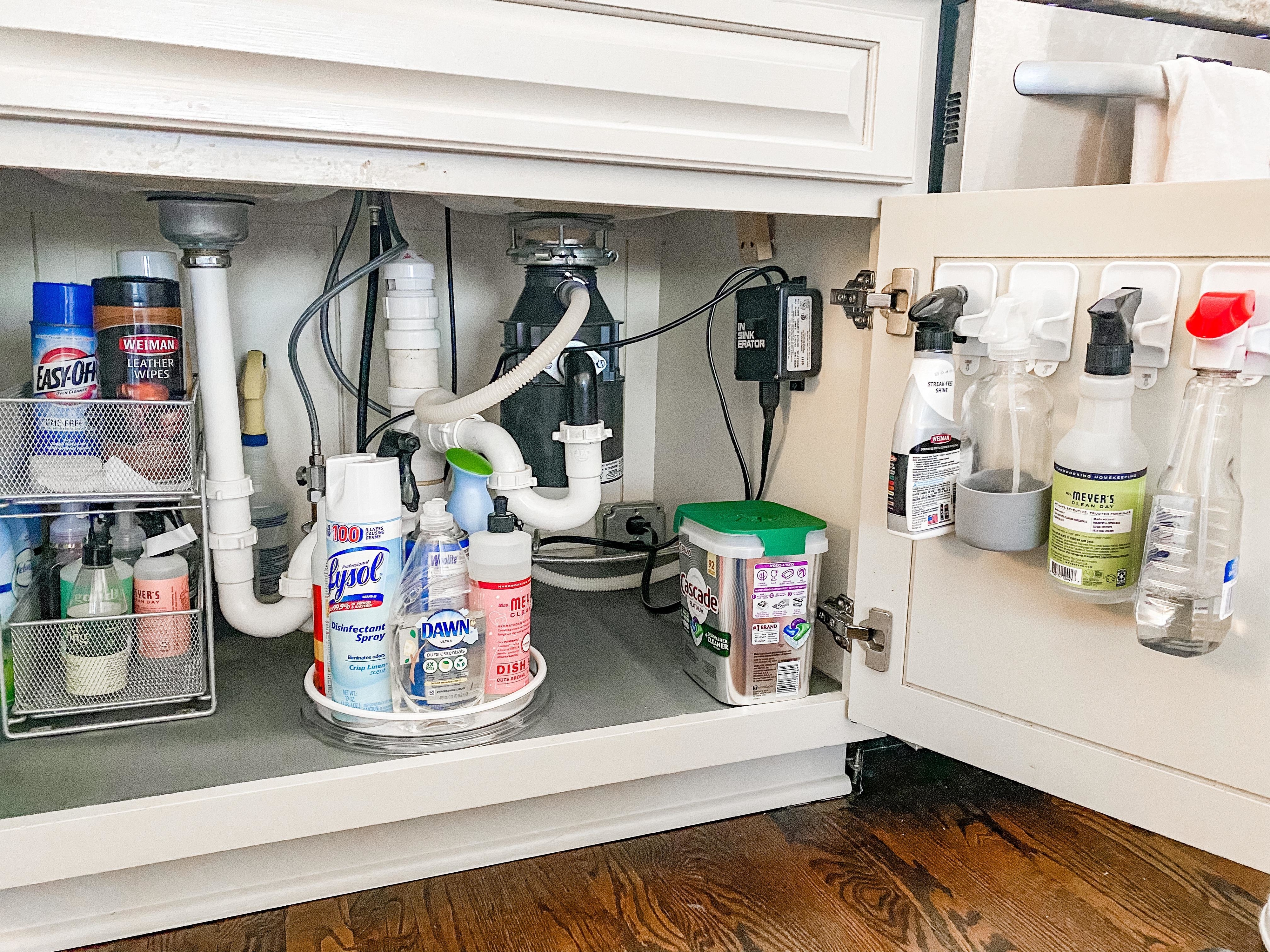 Spray cleaning bottles hanging on special hooks attached to a cabinet door