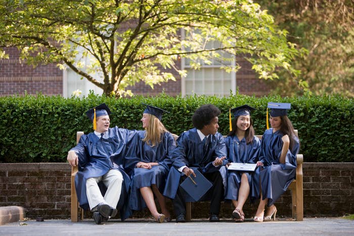 grads in their robes sitting on a bench