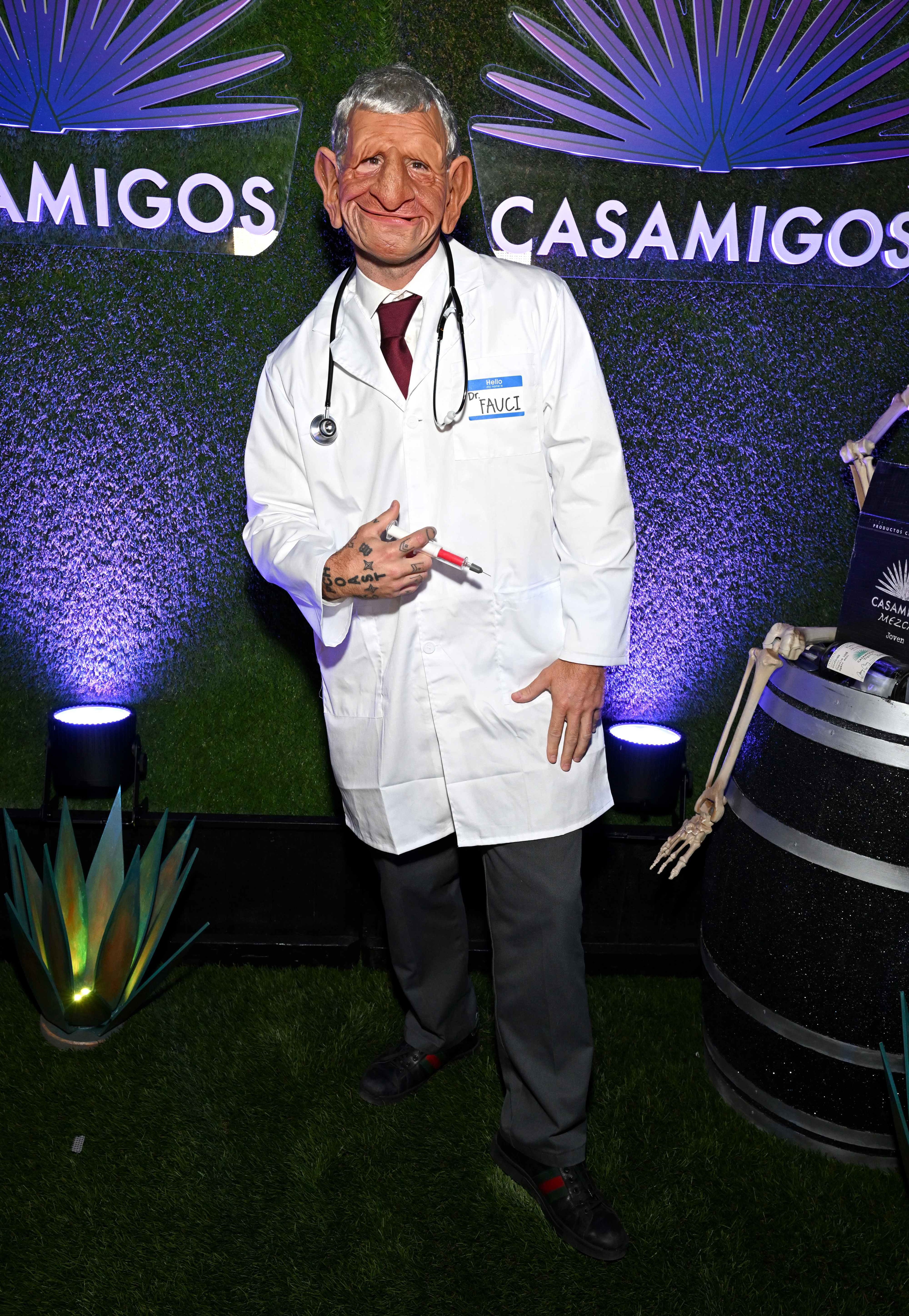 in a lab coat with a syringe and a comically over the top face mask